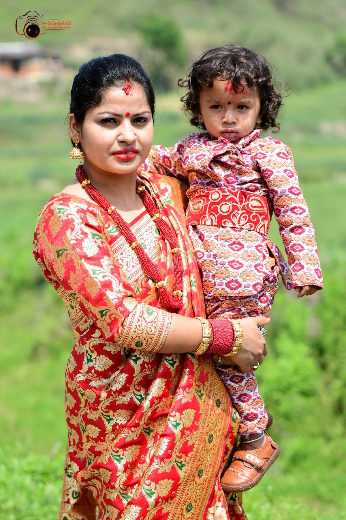 Mother in a red sari holding her child during a family session