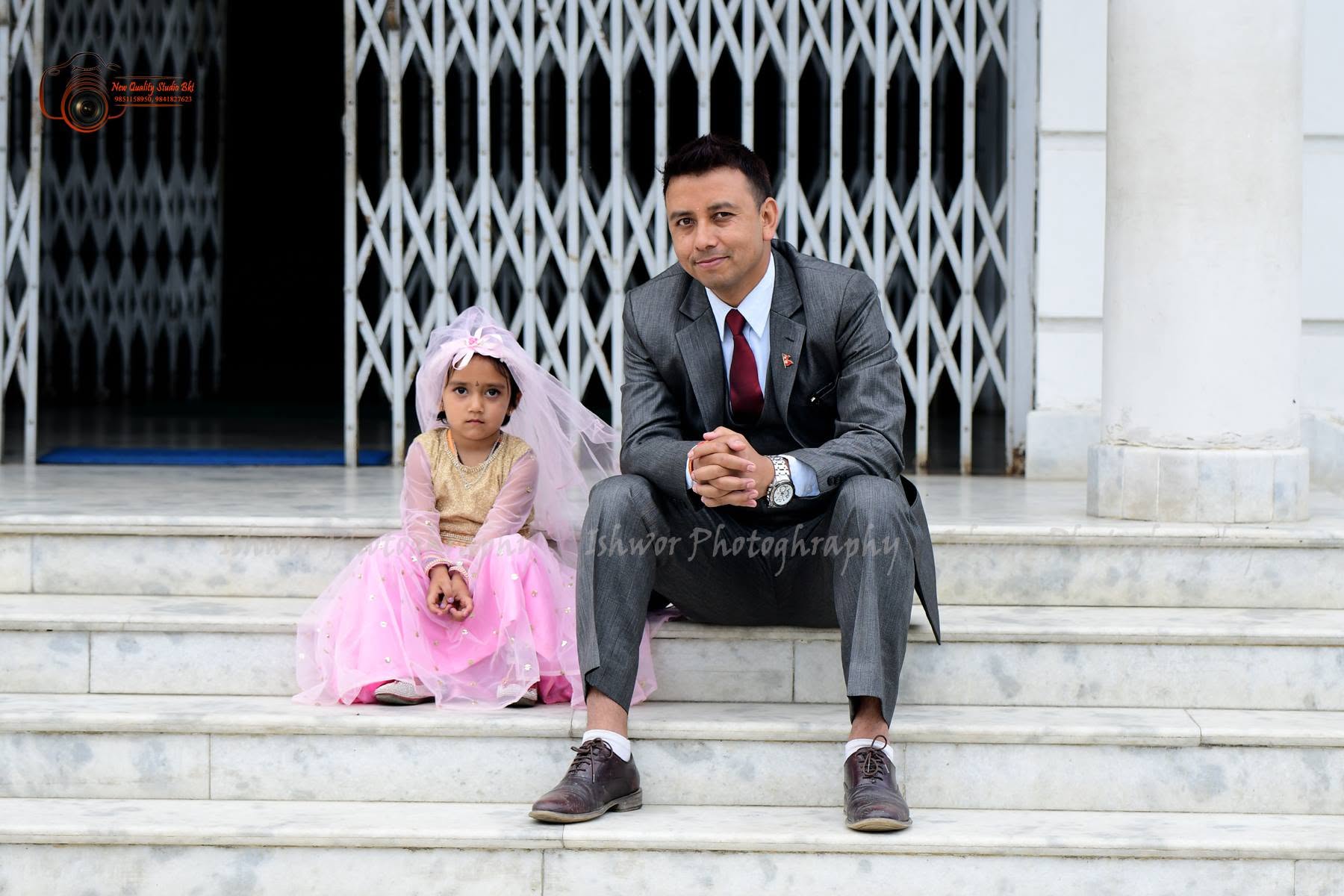 Father and daughter seated on temple steps in formal attire